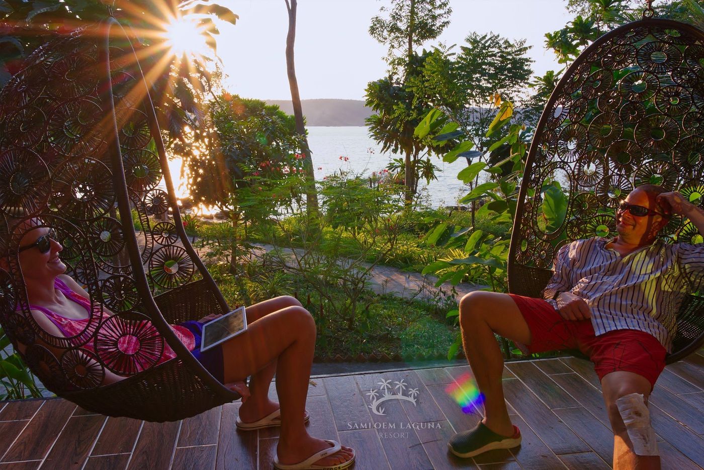 Couple relaxing in hanging chairs near the water at sunset